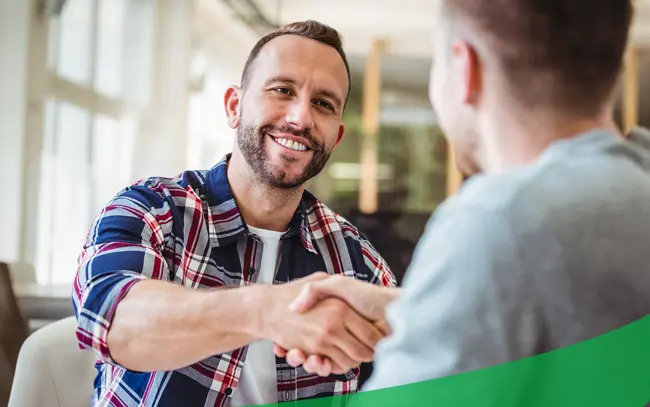 Friendly bank representative shaking hands with a customer—illustrating trust, personal service, and strong relationships built through local checking and savings accounts.